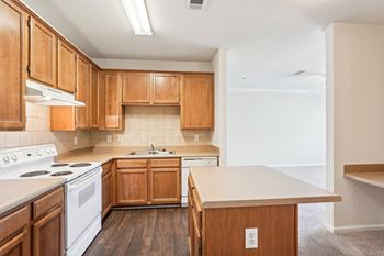 A kitchen with wooden cabinets and a white stove top oven with a large island.
